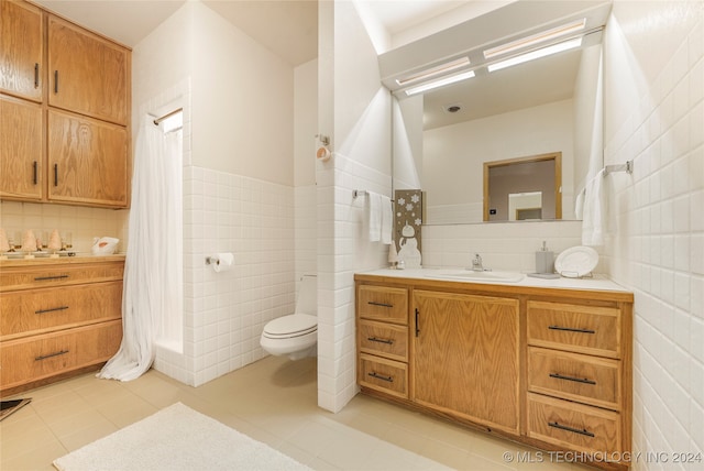 bathroom with vanity, tile patterned floors, decorative backsplash, toilet, and tile walls