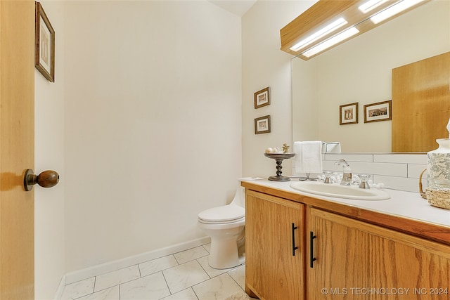 bathroom featuring vanity, toilet, and decorative backsplash