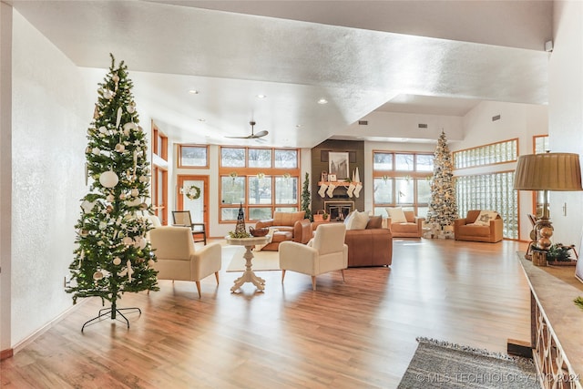 living room featuring ceiling fan, vaulted ceiling, and light wood-type flooring