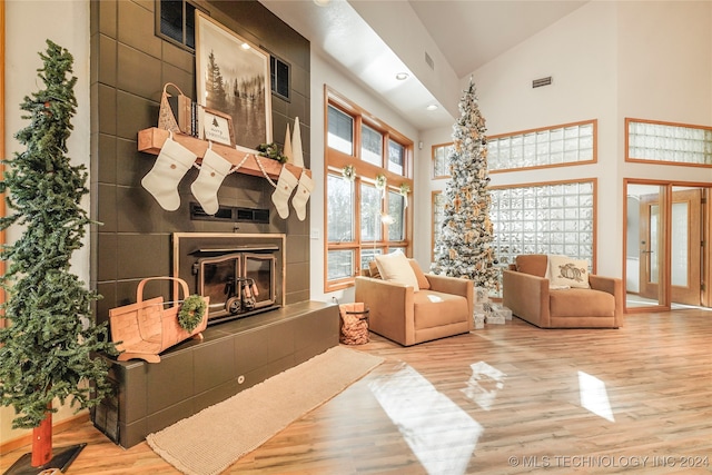 living room with wood-type flooring, a fireplace, and high vaulted ceiling