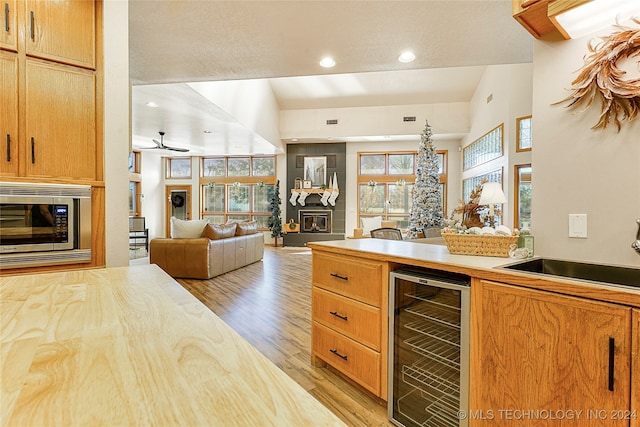 kitchen featuring vaulted ceiling, ceiling fan, sink, light hardwood / wood-style floors, and wine cooler