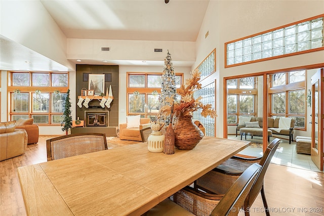 dining room featuring a fireplace, light hardwood / wood-style floors, and high vaulted ceiling