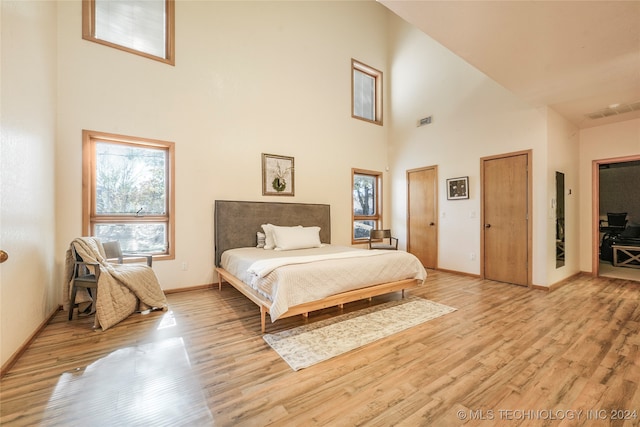 bedroom featuring a towering ceiling, light wood-type flooring, and two closets