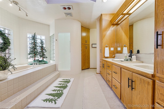 bathroom featuring tiled tub, tile patterned flooring, and vanity