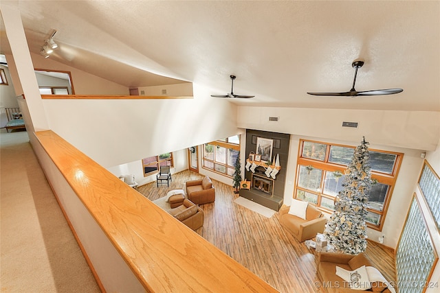 living room with ceiling fan, wood-type flooring, a wealth of natural light, and vaulted ceiling