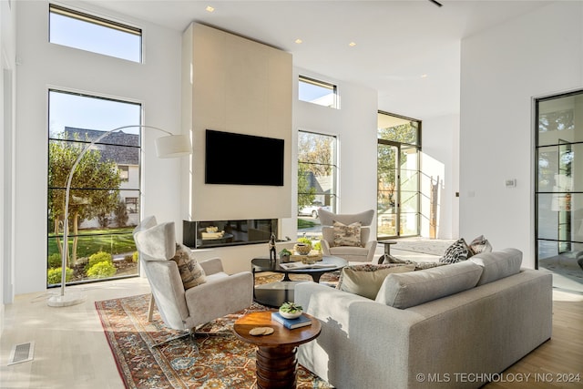 living room featuring a towering ceiling, hardwood / wood-style flooring, and a tiled fireplace