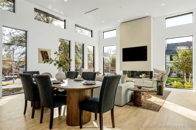 dining area with light wood-type flooring and a towering ceiling