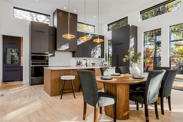 dining area with a high ceiling and light wood-type flooring