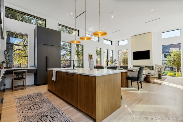 kitchen with a kitchen island with sink, plenty of natural light, hanging light fixtures, and a high ceiling