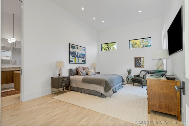 bedroom with light hardwood / wood-style floors, multiple windows, and ensuite bathroom