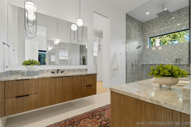 bathroom featuring tile patterned flooring, vanity, and a tile shower