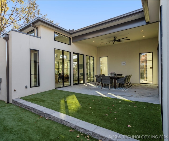 rear view of property with ceiling fan, a yard, and a patio