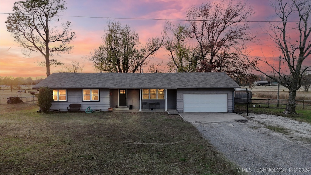 ranch-style house with a garage and a lawn