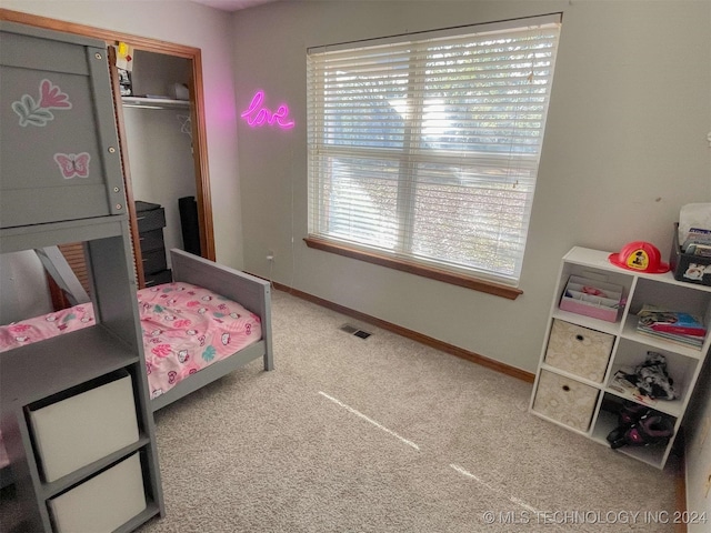 carpeted bedroom featuring multiple windows and a closet