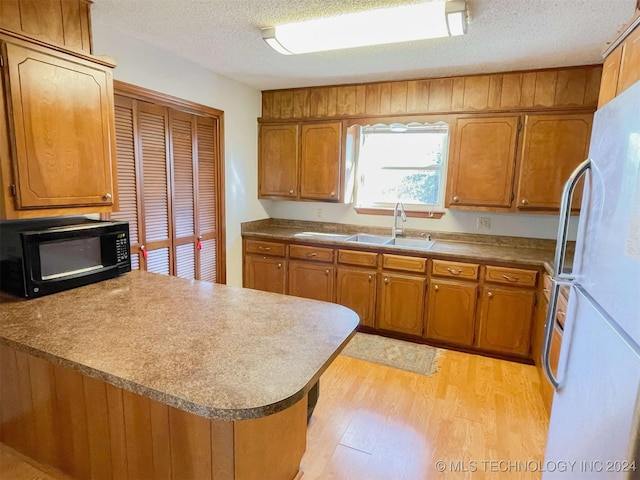 kitchen with sink, light hardwood / wood-style flooring, a textured ceiling, white fridge, and kitchen peninsula