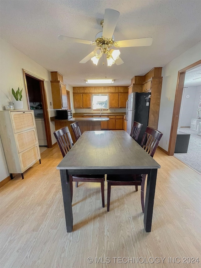 dining area featuring a textured ceiling, light hardwood / wood-style flooring, ceiling fan, and sink