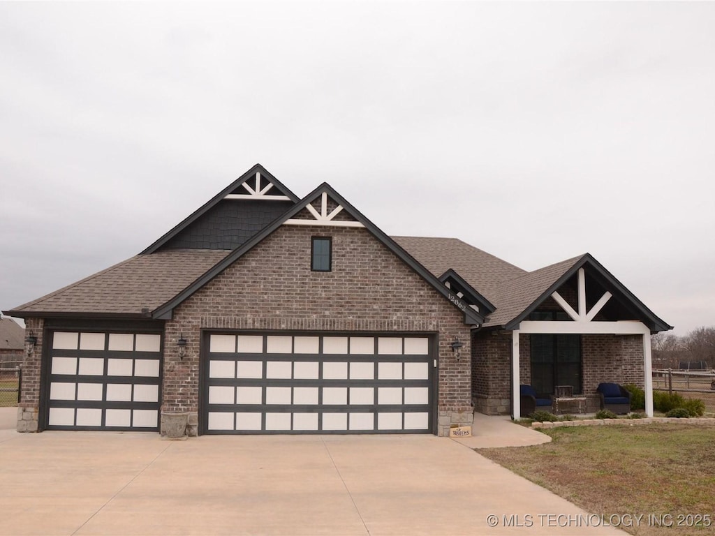 view of front of home with a garage, roof with shingles, concrete driveway, and brick siding