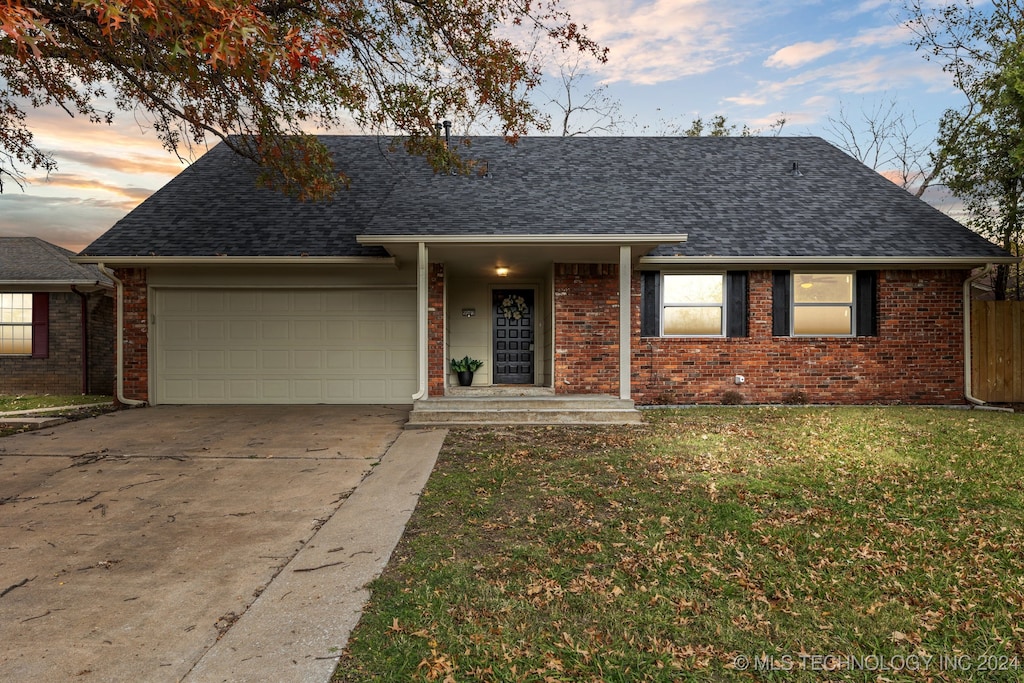 ranch-style house featuring a garage and a lawn