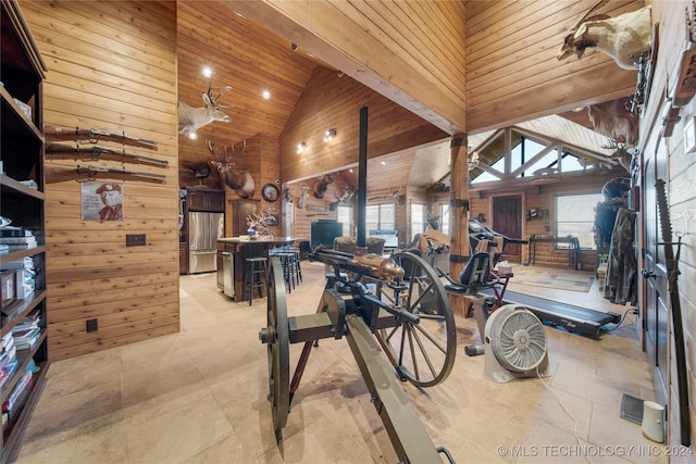 interior space featuring a skylight, high vaulted ceiling, a wealth of natural light, and wooden walls