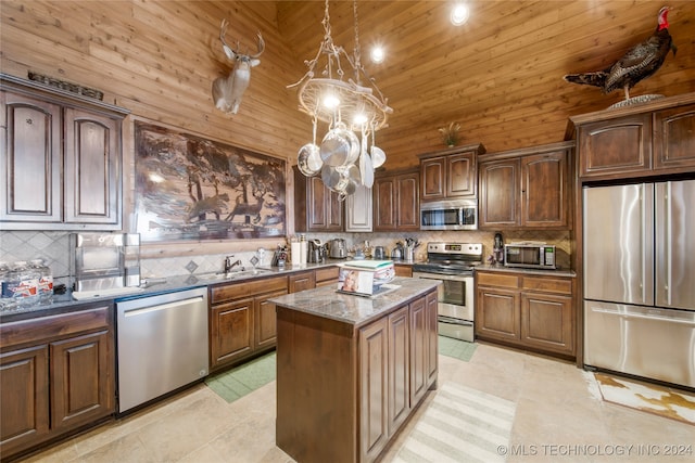 kitchen featuring tasteful backsplash, a center island, a towering ceiling, and appliances with stainless steel finishes