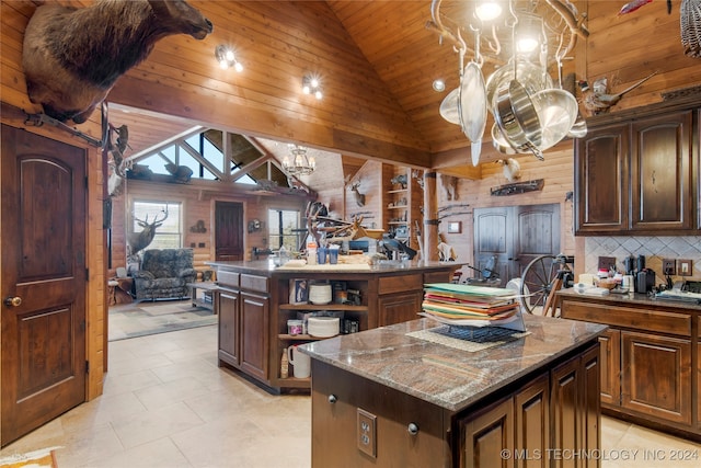 kitchen with wood walls, wooden ceiling, dark stone countertops, a kitchen island, and dark brown cabinetry