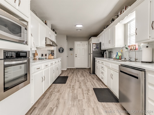 kitchen featuring sink, white cabinets, stainless steel appliances, and light wood-type flooring