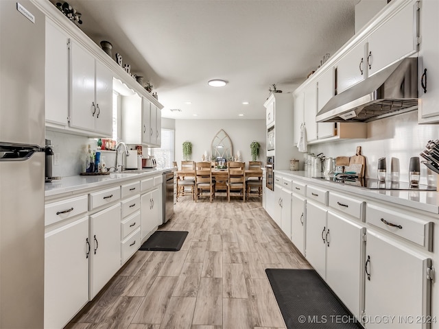 kitchen with white cabinets, sink, appliances with stainless steel finishes, and light hardwood / wood-style flooring