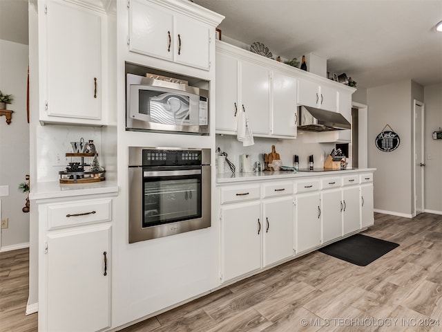 kitchen with tasteful backsplash, light hardwood / wood-style flooring, white cabinets, and appliances with stainless steel finishes