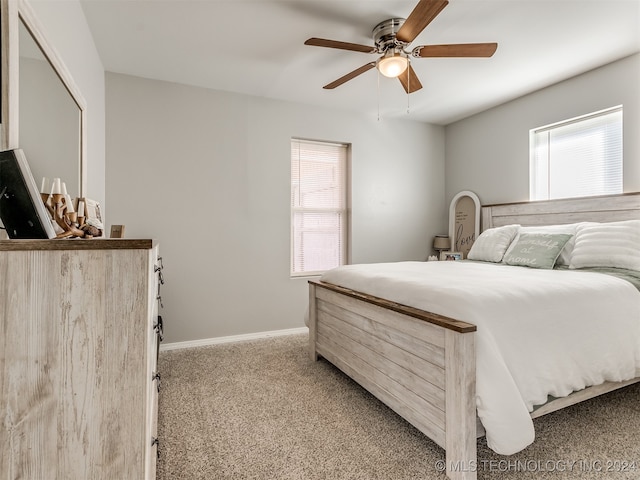 bedroom with multiple windows, ceiling fan, and light colored carpet