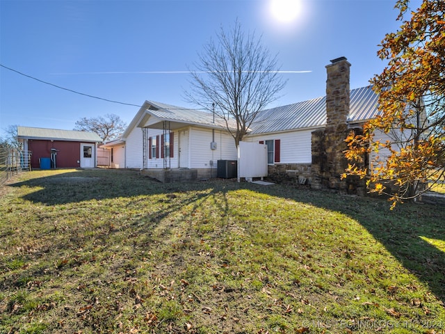 rear view of house with a lawn and cooling unit