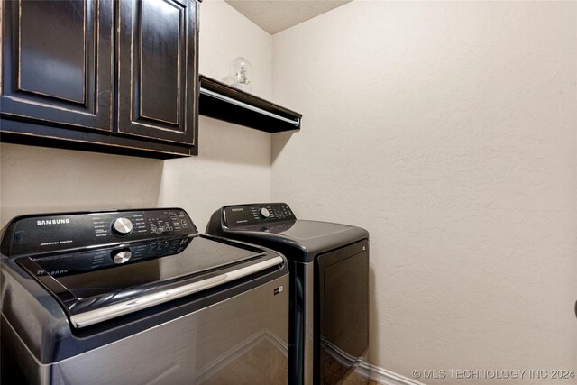 washroom with washer and dryer, cabinet space, and a textured wall