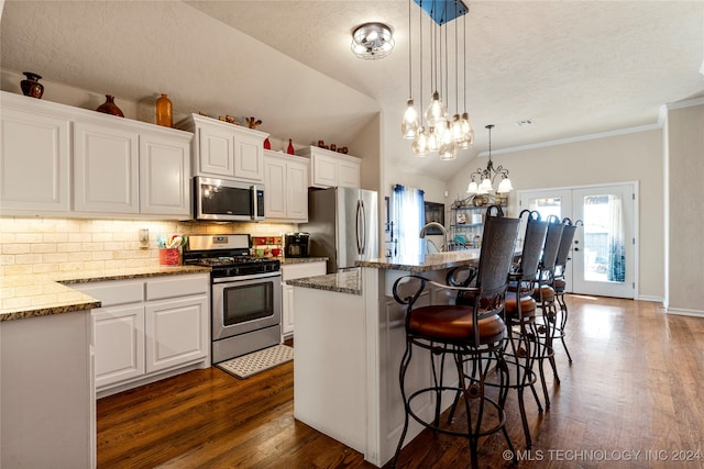 kitchen featuring dark hardwood / wood-style floors, an island with sink, stainless steel appliances, and vaulted ceiling