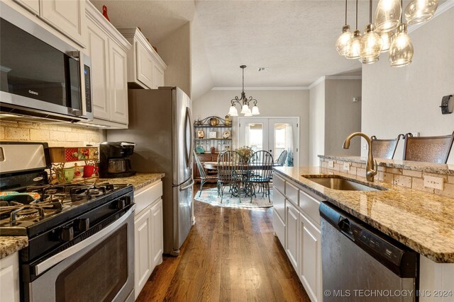 kitchen featuring dark wood-type flooring, a sink, white cabinets, appliances with stainless steel finishes, and tasteful backsplash