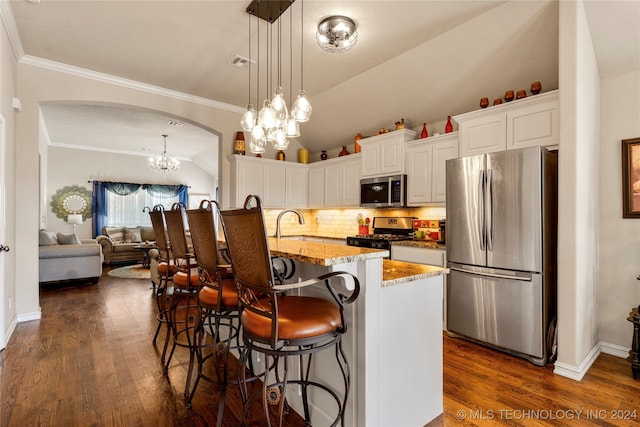 kitchen featuring hanging light fixtures, dark wood-type flooring, stainless steel appliances, a center island with sink, and white cabinets