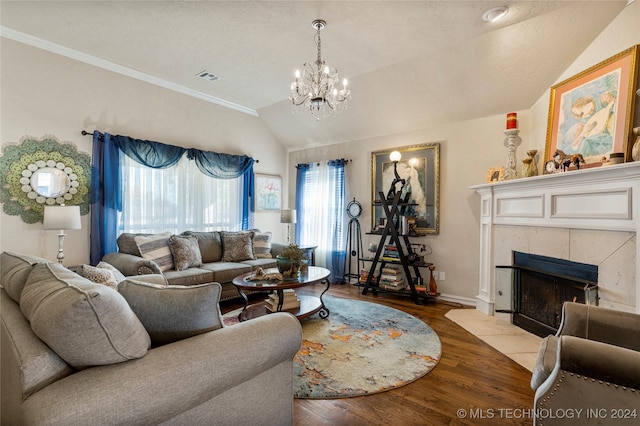 living room featuring hardwood / wood-style flooring, vaulted ceiling, a wealth of natural light, and a tiled fireplace