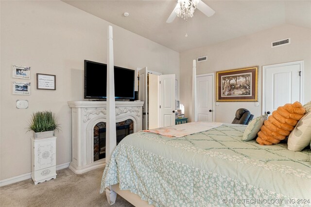 bedroom featuring light colored carpet, visible vents, vaulted ceiling, and a glass covered fireplace