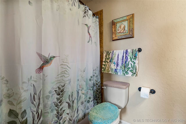 bathroom featuring a shower with curtain and toilet