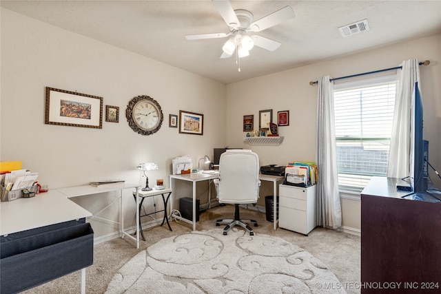 carpeted home office featuring ceiling fan