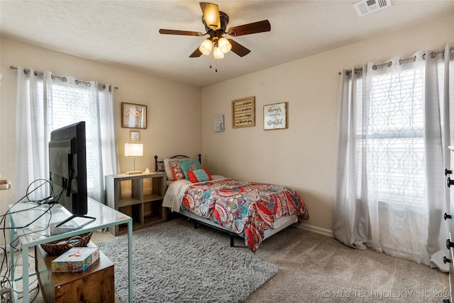 carpeted bedroom with multiple windows, ceiling fan, and a textured ceiling