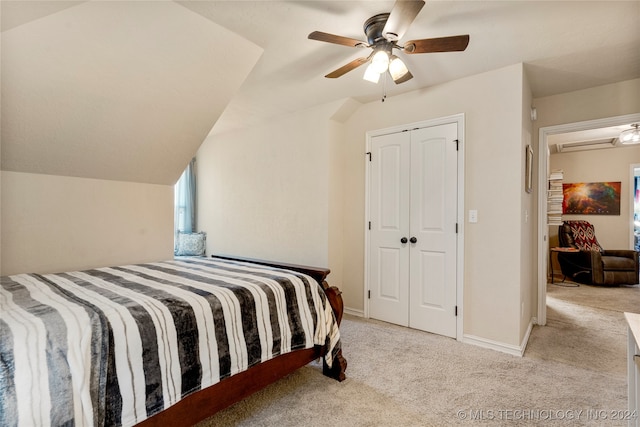 bedroom featuring ceiling fan, a closet, light carpet, and vaulted ceiling