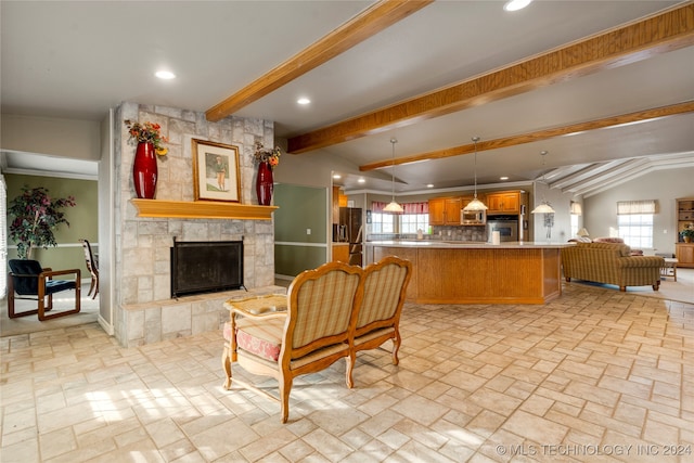 kitchen with stainless steel appliances, a stone fireplace, lofted ceiling with beams, kitchen peninsula, and decorative light fixtures