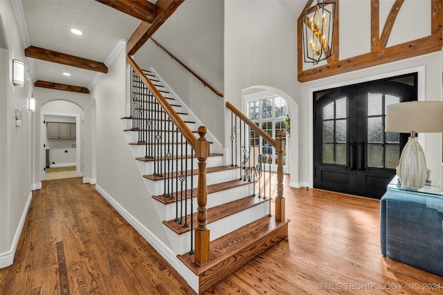 foyer featuring hardwood / wood-style floors, plenty of natural light, beamed ceiling, and french doors