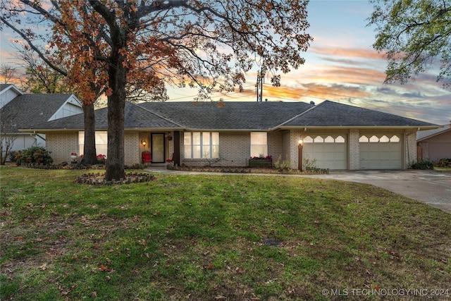 ranch-style home with a garage and a lawn