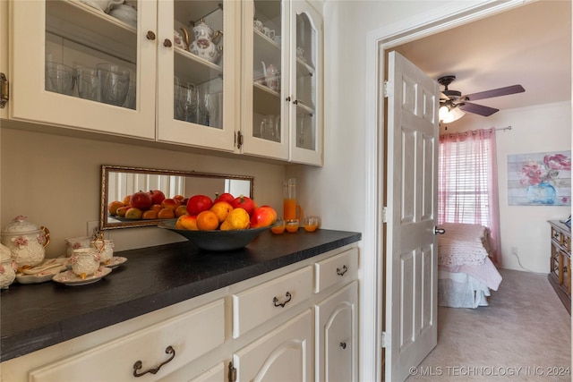 bar featuring ceiling fan, light colored carpet, and white cabinetry