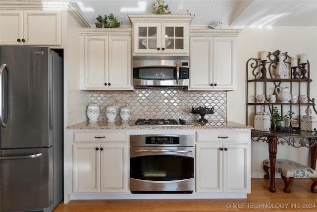 kitchen featuring stainless steel appliances, light wood-type flooring, light stone counters, and tasteful backsplash