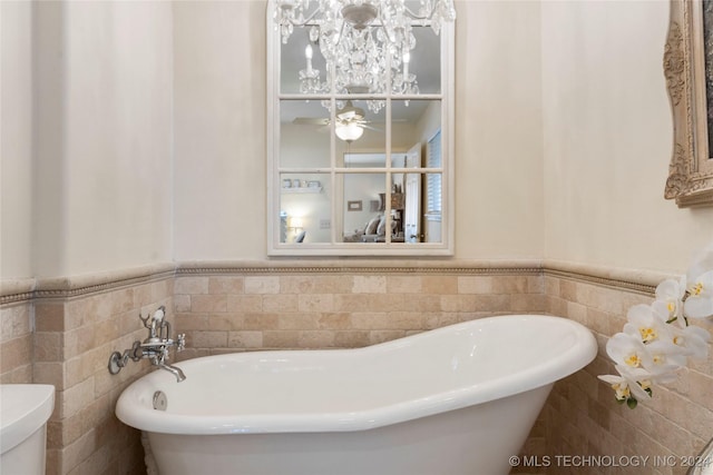 bathroom with tile walls, a tub, and toilet