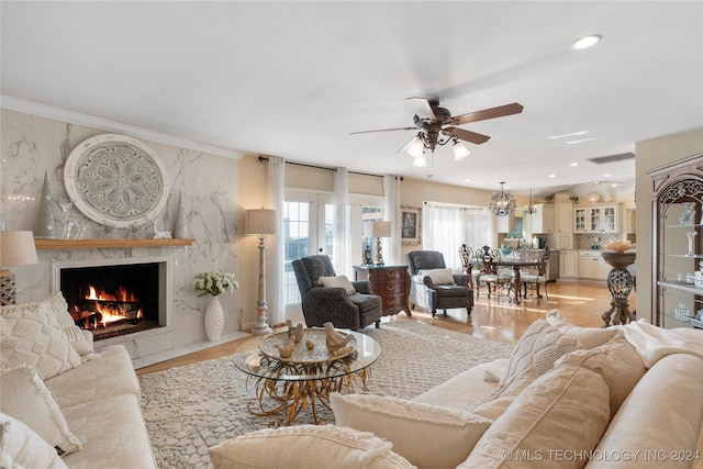 living room with a premium fireplace, ornamental molding, ceiling fan, and light wood-type flooring