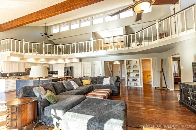 living room with ceiling fan, beam ceiling, dark hardwood / wood-style flooring, and a towering ceiling