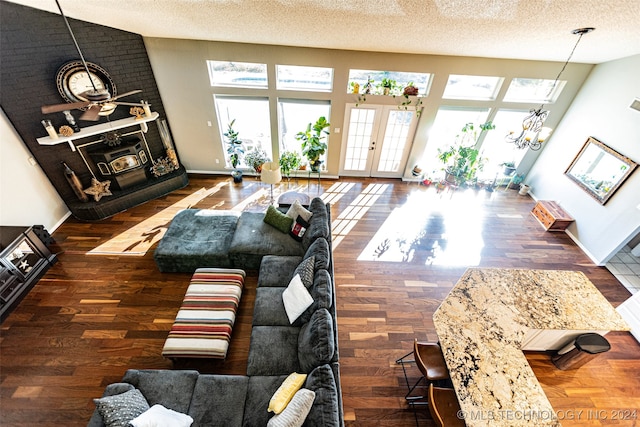 living room with dark wood-type flooring, high vaulted ceiling, french doors, a textured ceiling, and a chandelier