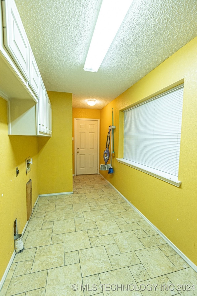 laundry area with cabinets, washer hookup, a textured ceiling, and hookup for an electric dryer